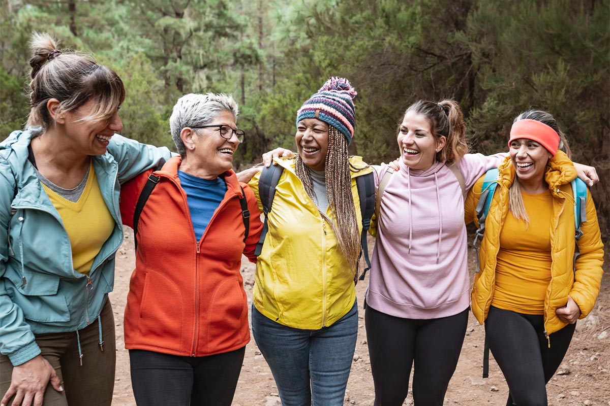 Group of women with different ages and ethnicities having fun walking in foggy forest